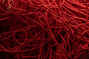 Chaotic interlacing of red rope. Abstract geometric background pattern, curves and curves, knots and weaves. Like spaghetti. Design and texture for sewing clothes, creativity.