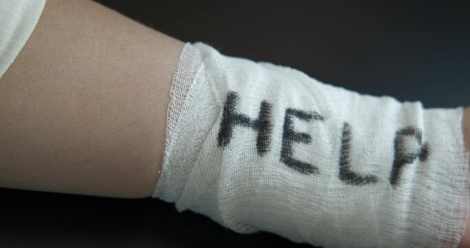 Suicide prevention. A view of a bandaged hand with word help because of suicide problems.