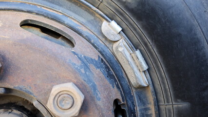 Lead weight on black car rims.  Lead-weighted wheel balancing for vehicle wheel balance while in...