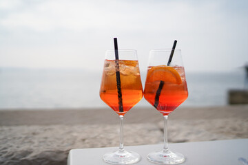 Aperol drink on white table with blue background. Sunshine and palm leaf shadow drink modern still life. Summer, party, tropical and freshness concept