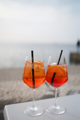 Aperol drink on white table with blue background. Sunshine and palm leaf shadow drink modern still life. Summer, party, tropical and freshness concept