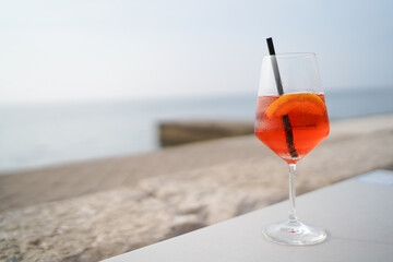 Aperol drink on white table with blue background. Sunshine and palm leaf shadow drink modern still life. Summer, party, tropical and freshness concept