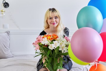 Portrait of birthday girl teenager with bouquet of flowers and balloons at home