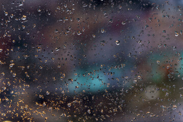 Abstract background with raindrops on a window glass at blurred night background.