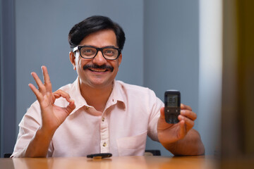 Man in happy mood while blood sugar level is showing normal on Glucometer