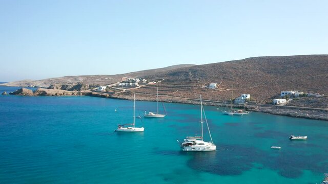Aerial flying through sailing boats anchored on emerald sea, Karavostasis Bay - Greece
