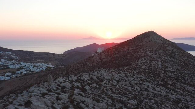 Aerial flying mountain hill towards Picturesque Panagia Church at Stunning Sunset, Folegandros Island