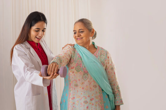 Senior woman exercising with the help of nurse