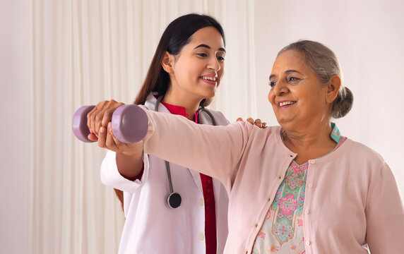 Senior woman exercising with the help of lady doctor
