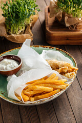Fish and chips dish with potato fries and creamy sauce
