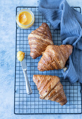 French croissant. Freshly baked croissants with honey on blue concrete background.