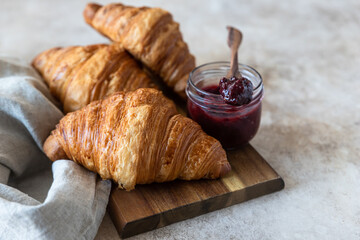 Fresh crispy croissants with jam, concrete background. Homemade bakery for tasty breakfast.