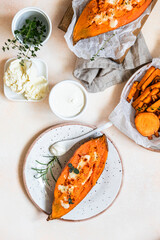 Baked sweet potatoes with mozzarella, herbs and creamy dip on concrete background. Top view.