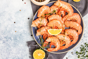 Fresh shrimps or prawns with lime, pepper and herbs on blue concrete background. Seafood. Top view.