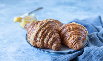 French croissant. Freshly baked croissants with honey on blue concrete background.