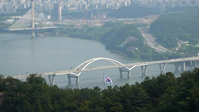 A view of the Han River and the Guri-Amsa Bridge in Seoul, South Korea as seen from them Acha Mountain hiking trail on a smoggy day