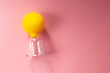 Silicone can for vacuum massage. Yellow cans for massage on a pink background. Devices for vacuum massage skin care. 