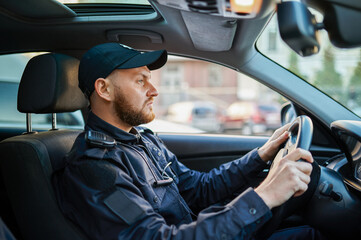 Male police officer in uniform poses in the car