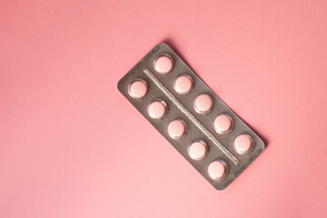 Pink pills in a blister pack on a pink background. 