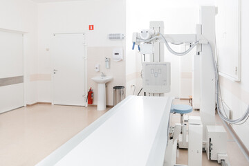 X-ray department in modern hospital. Radiology room with scan machine with empty bed. Technician adjusting an x-ray machine. Scanning chest, heart, lungs in modern clinic office.