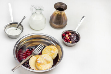 Berries, fork and cottage cheese pancakes and berries in metal bowl.
