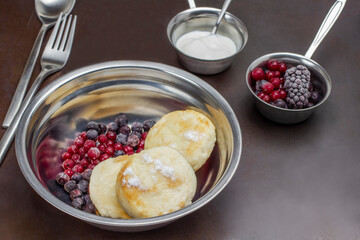 Cottage cheese pancakes and berries in metal bowl.