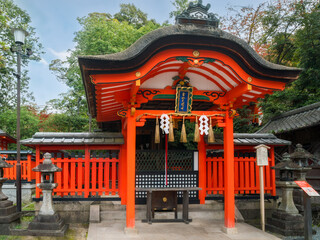 Beautiful traditional Japanese architecture with a curved roof and a colourful building structure on the grounds at Fushimi Inari Taisha shrine in Kyoto, Japan. Language: 'Salt Mountain Great Myojin'