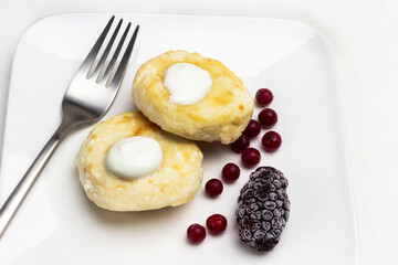 Fork, berries and cottage cheese pancakes on white plate.