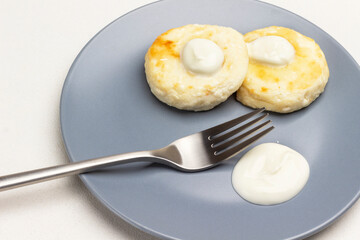 Cottage cheese pancakes with yogurt and fork on gray plate