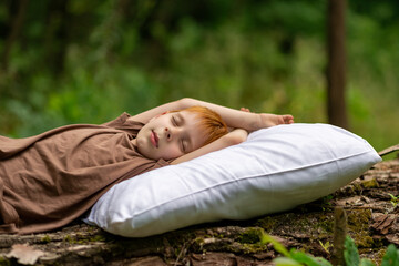 Healthy baby sleep concept. A young boy sleeps on a pillow in the woods.