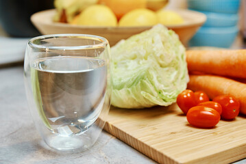 Glass of pure water and fresh vegetables on table