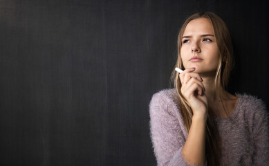 Pretty, young female student in front of a blackboard during class