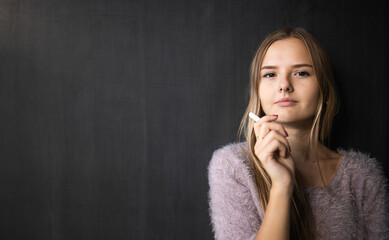Pretty, young female student in front of a blackboard during class