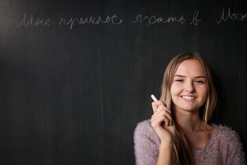 Pretty, young female student in front of a blackboard during class