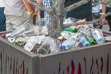 Garbage from cans and plastic and paper in a pot with a tree