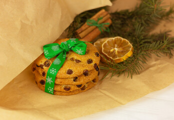 raisin cookies with christmas green ribbon, lemon, cinnamon and spruce branch on wrapping craft paper