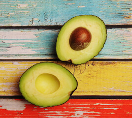 Avocado cut in half on a colored wooden background