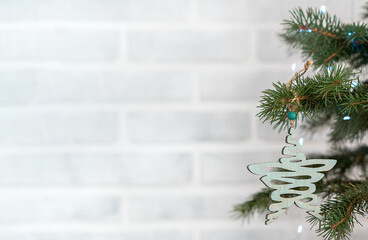 The tree is decorated with a star made from natural materials and lights against a white brick wall with space for text. Ecological lifestyle and minimalism concept.