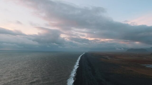 Static aerial slow motion clip of black sand shoreline in Iceland. Wide angle.