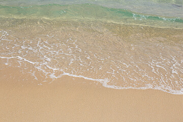 Wave of water on clear sandy beach.