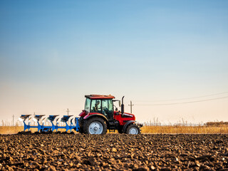 Farmer in tractor plowing preparing stubble field cultivating for seeding crops.