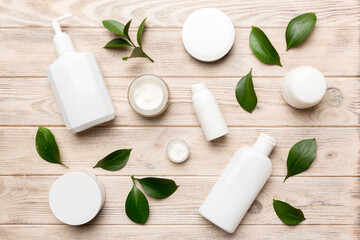 Obraz na płótnie Canvas Organic cosmetic products with green leaves on wooden background. Flat lay