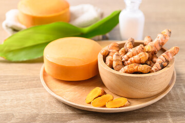 Turmeric soap and fresh turmeric root in a bowl, herbal organic soap for skin care