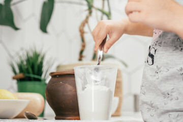 Hands of little girl bake apple pie in kitchen. Child puts flour in measuring cup. Kid cooking food. Top view