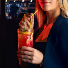 Young woman in a bar or club having fun - in the background her bar, focus on the glass mojito she...