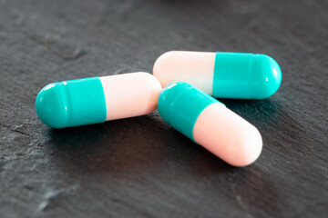 Close up of colorful pills. Two-tone drugs and supplements. Capsules to be swallowed wrapped in the blister. Three tablets out of the blister.