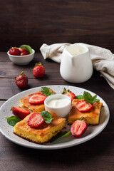 Cottage cheese casserole with strawberries and mint. Delicious homemade dessert made of curd and fresh berries with cream. dark wooden background, copy space.
