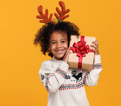 Christmas holidays. Happy little african american boy wearing red deer antlers with xmas gift box