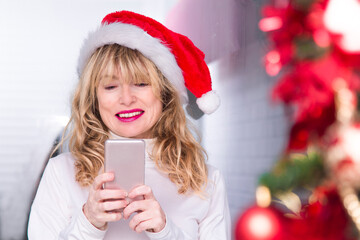 woman with christmas santa claus hat using mobile phone