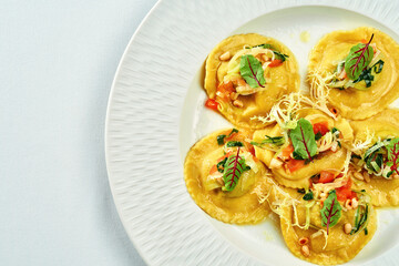 Ravioli with different fillings in sauce and parmesan in a white plate
